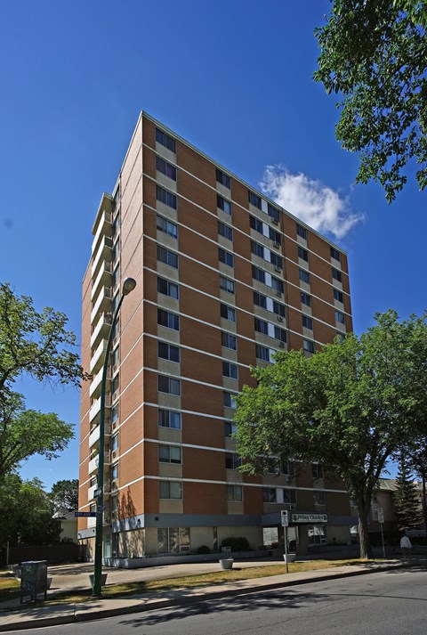 A tall building with a brown and beige facade stands on a street corner.