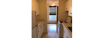 A kitchen with white cabinets and a refrigerator.