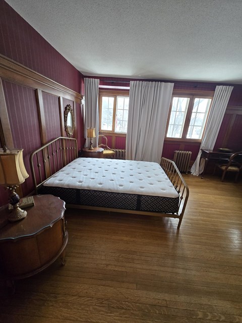 A bedroom with a large bed and wooden floors.