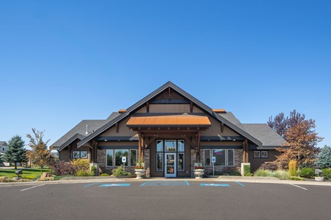 A building with a brown roof and glass windows and a parking lot in front.