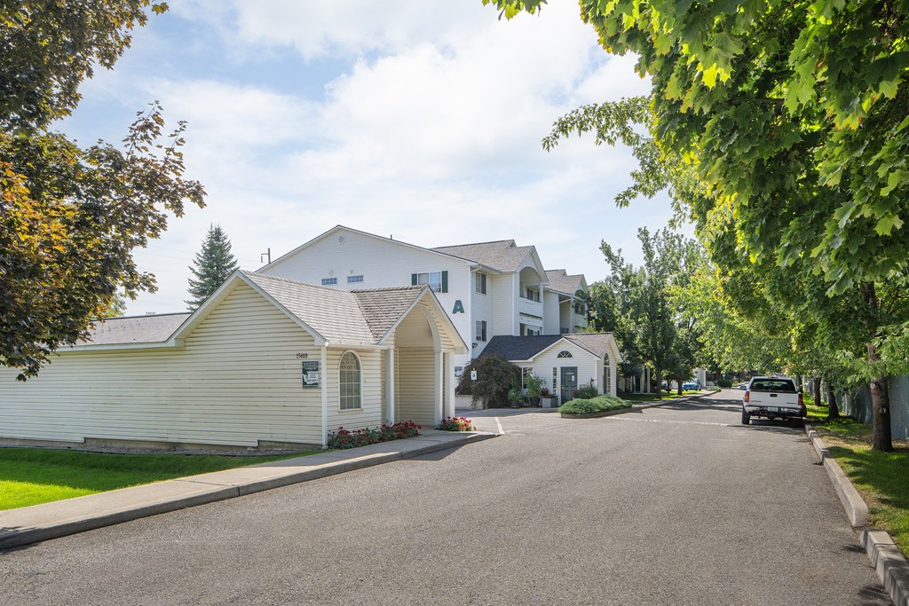 a street with white houses and a car parked on the side of the road