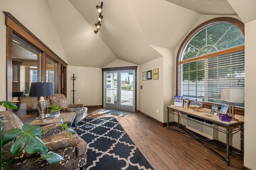 a living room with a large arched window and a couch and a desk