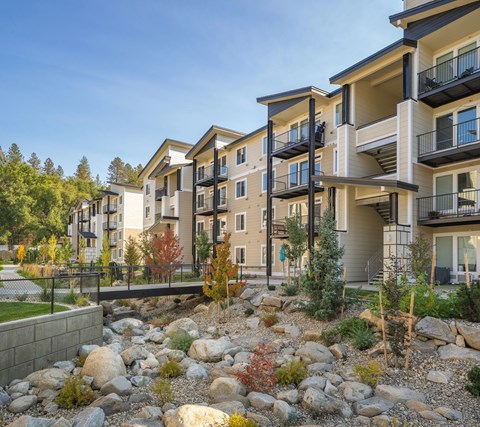 A modern apartment complex with a landscaped rock garden in front.