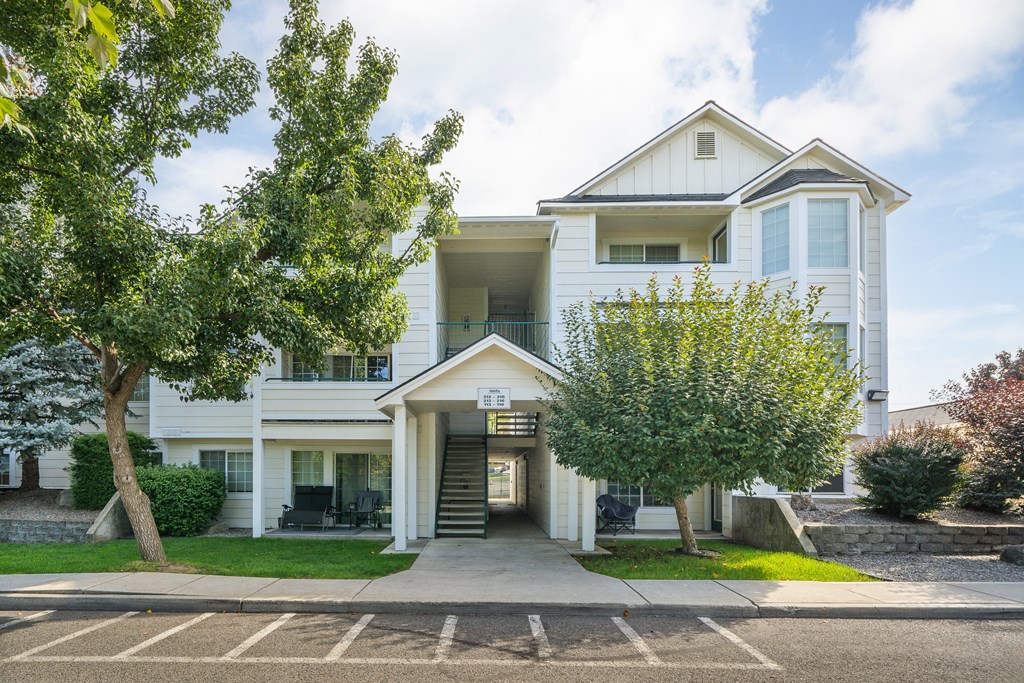 a white apartment building with trees in front of it
