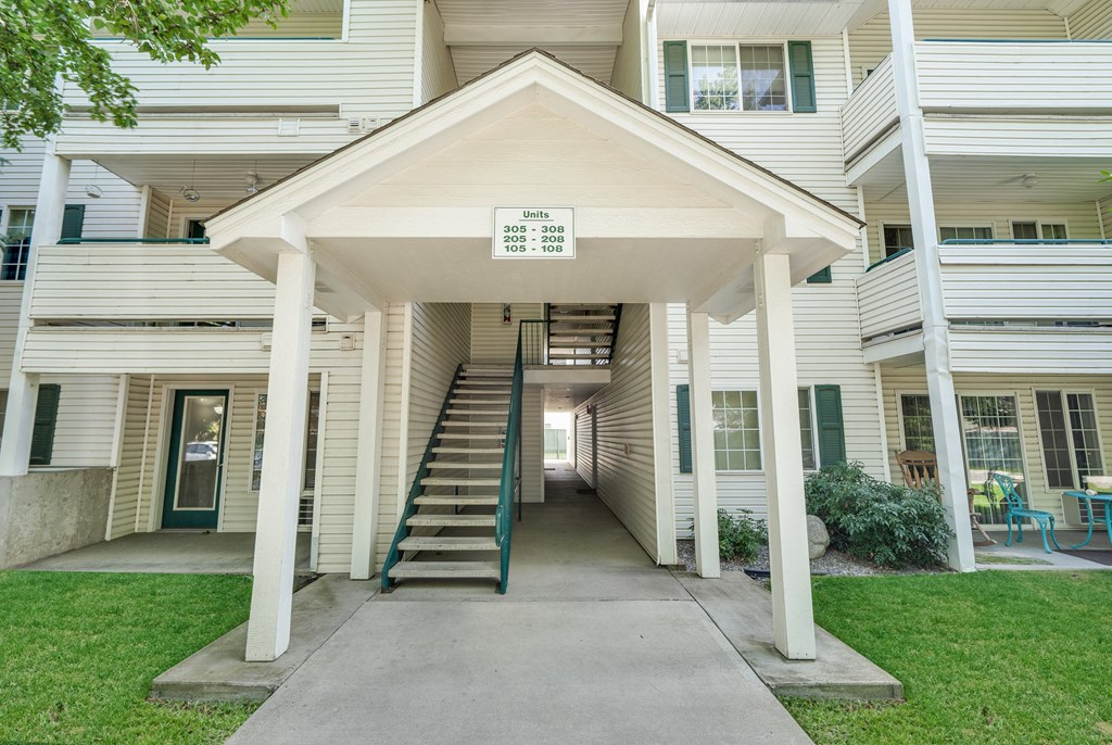the entrance to a white apartment building with stairs and a porch