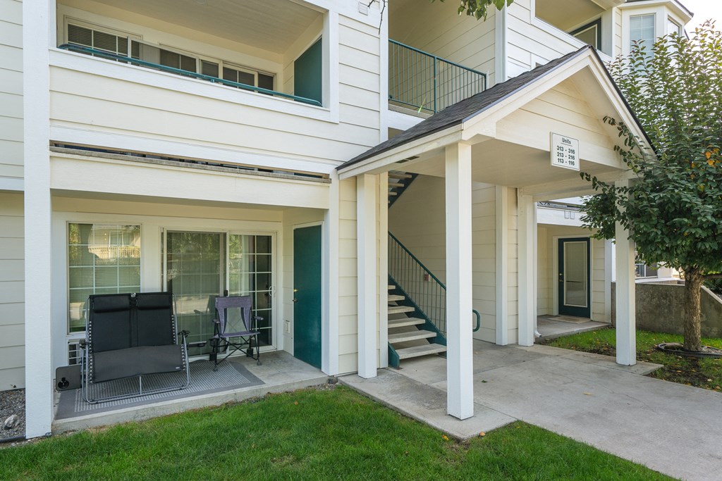 a patio with two chairs and a staircase in front of a house