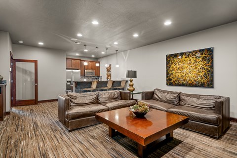 A living room with a brown couch and a painting on the wall.