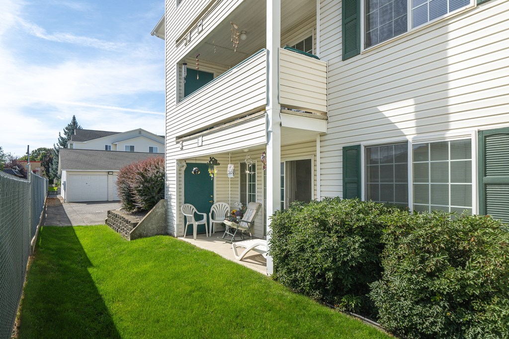 the side of a white house with a patio and lawn