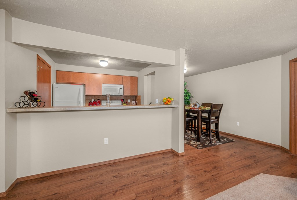 the living room and kitchen of an apartment with a wood floor and a kitchen island