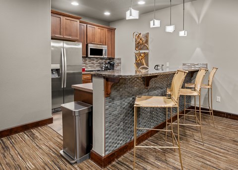 A kitchen with a refrigerator, microwave, and a dining table with chairs.