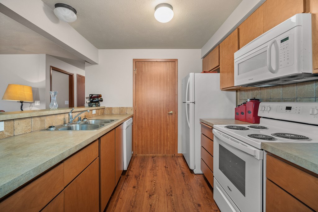 a kitchen with white appliances and wooden cabinets and a white refrigerator
