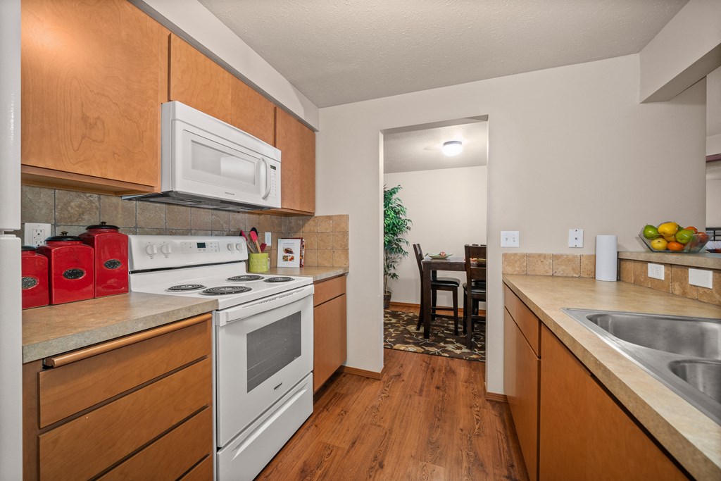full kitchen with white appliances and wooden cabinets and a dining room with a table