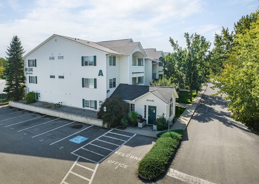a large white apartment building with a parking lot and a driveway