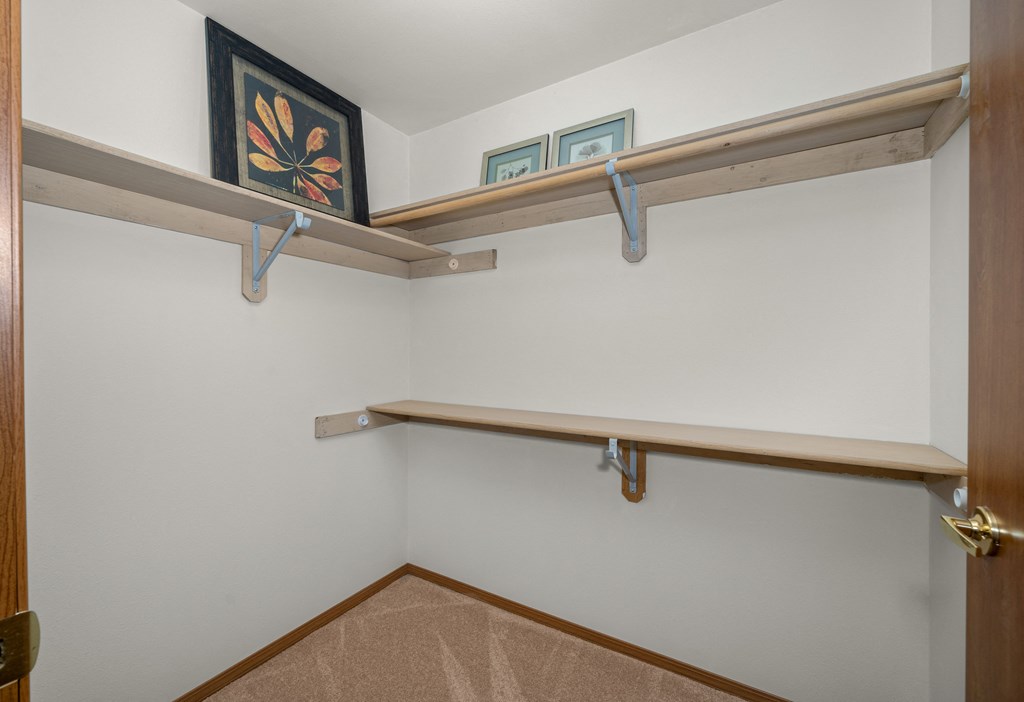 a walk in closet with a shelf and hooks on the wall