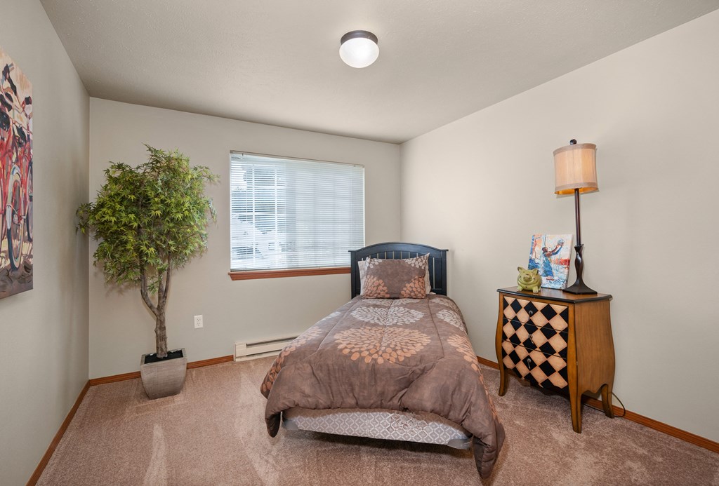 a bedroom with a bed and a tree in the corner