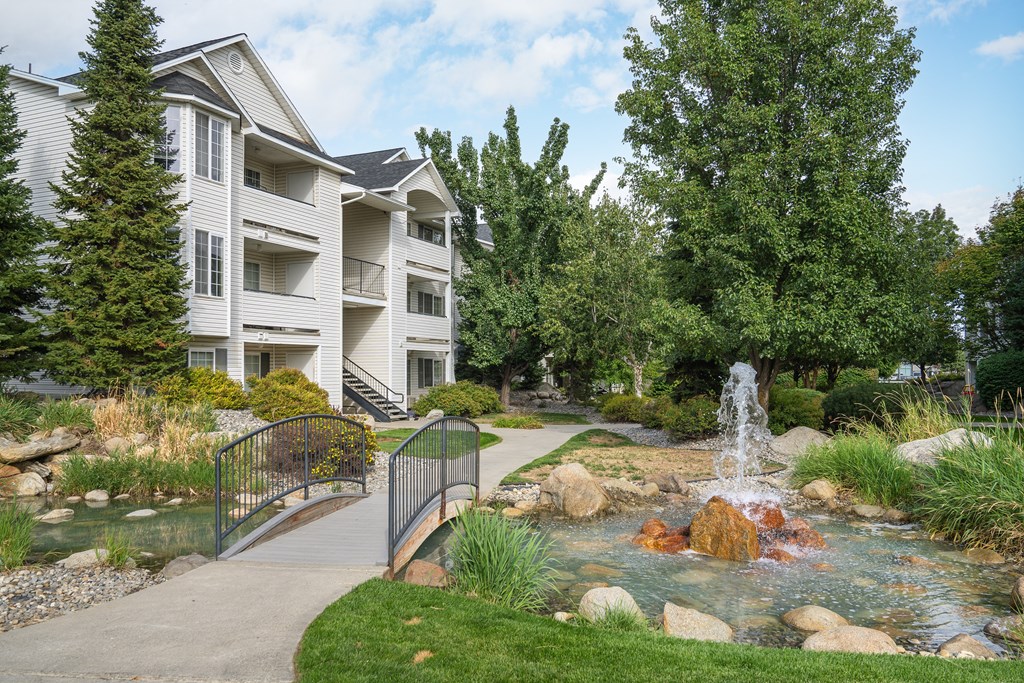 a fountain sits in the middle of a stream in front of a building