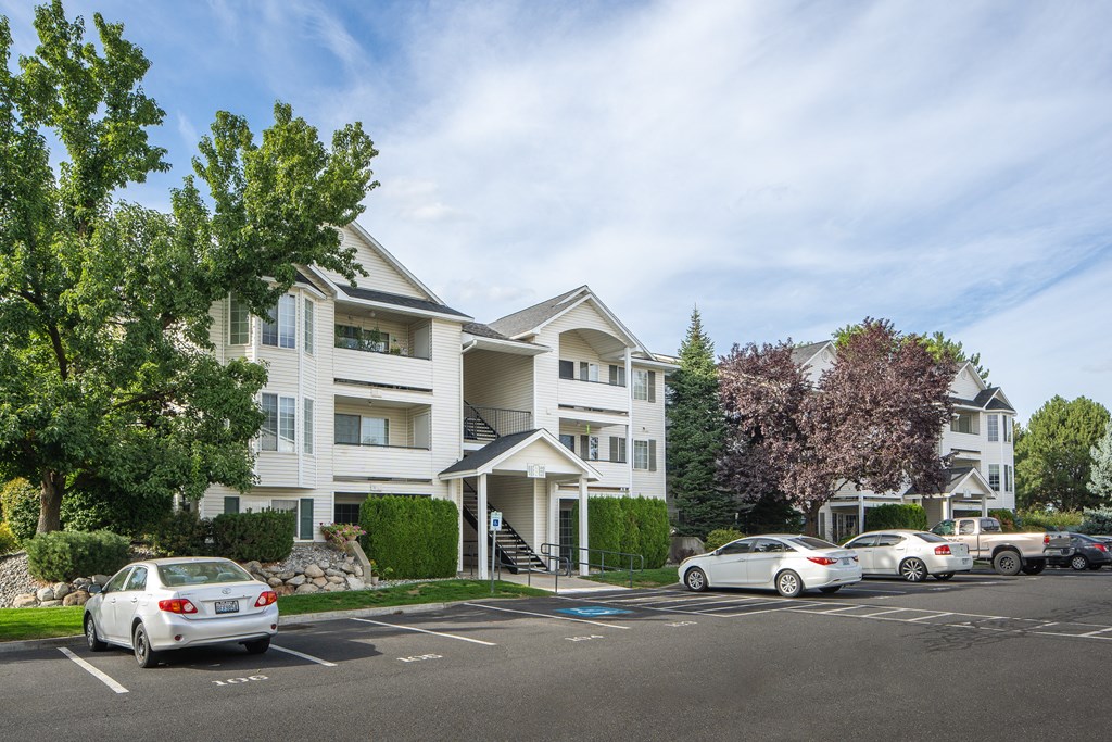 an apartment building with cars parked in a parking lot