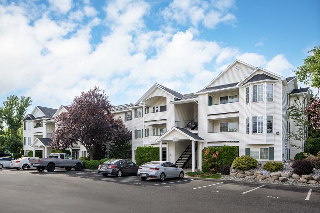 a row of white apartment buildings with cars parked in front of them