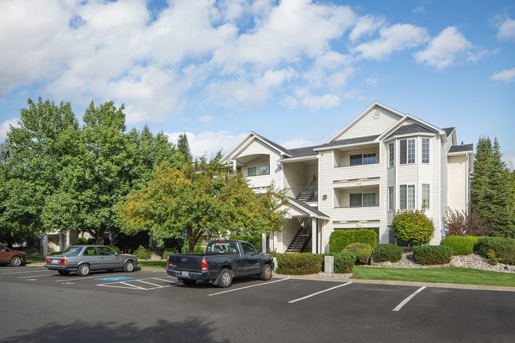 a large white house with cars parked in a parking lot