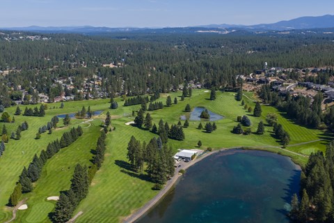 A golf course with a lake and a small building.