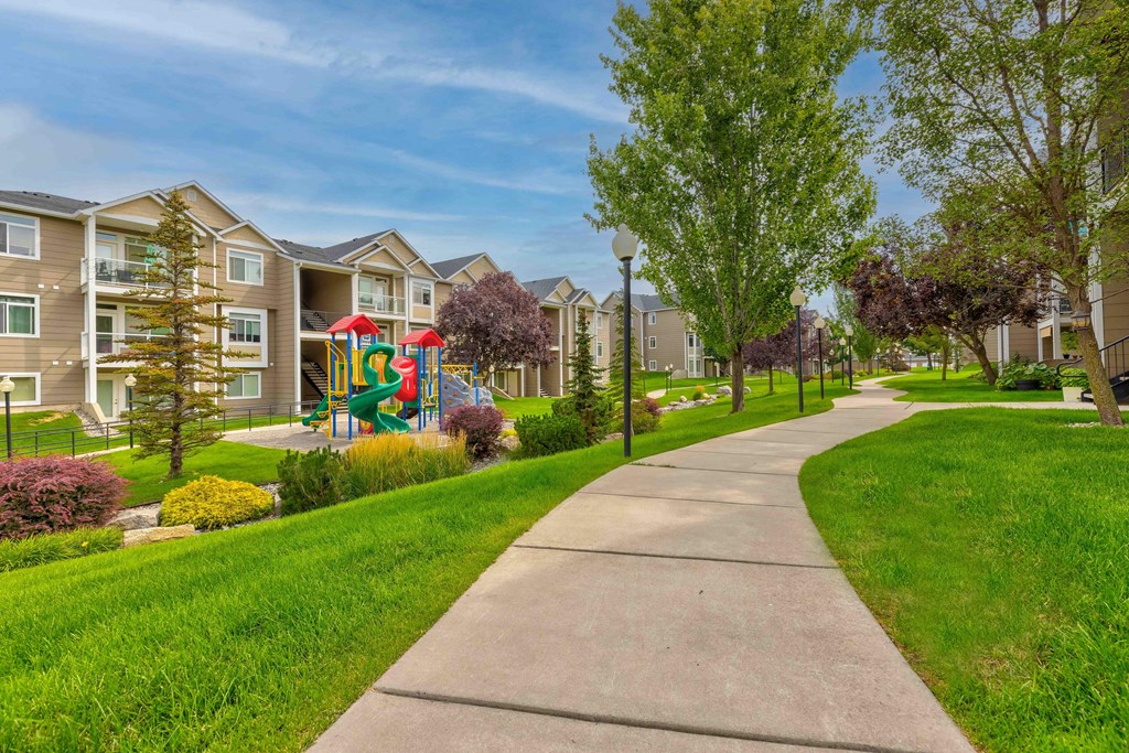 a sidewalk leading to an apartment building with a playground