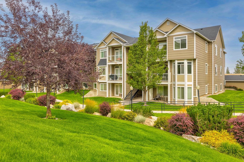 an apartment building with lush green grass and flowering trees