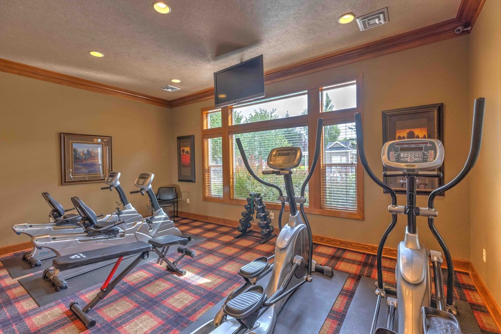 a gym with cardio equipment and a window