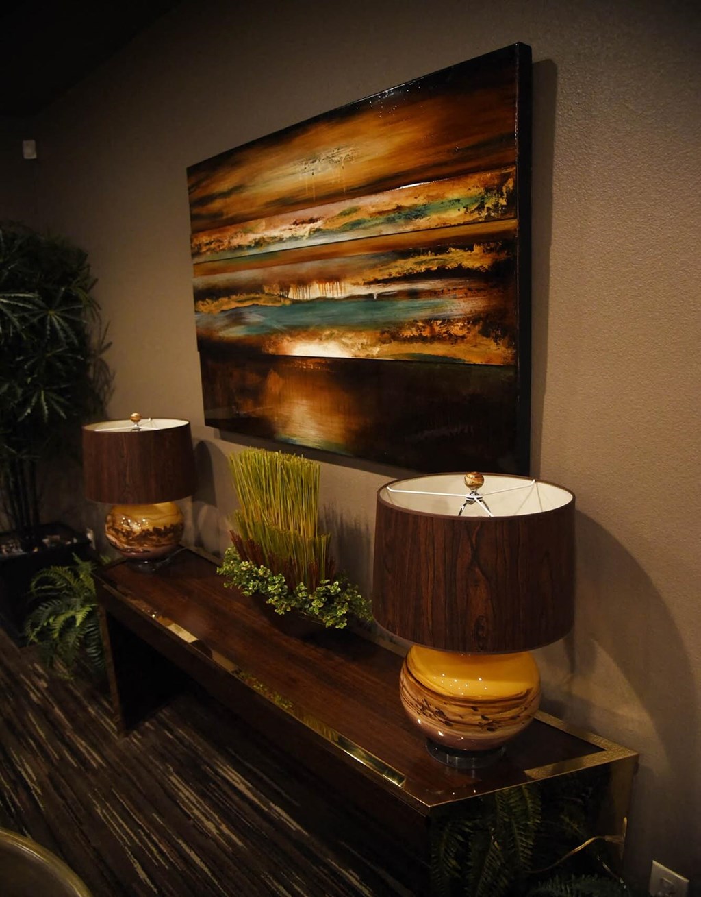 two lamps on a table with a painting on the wall