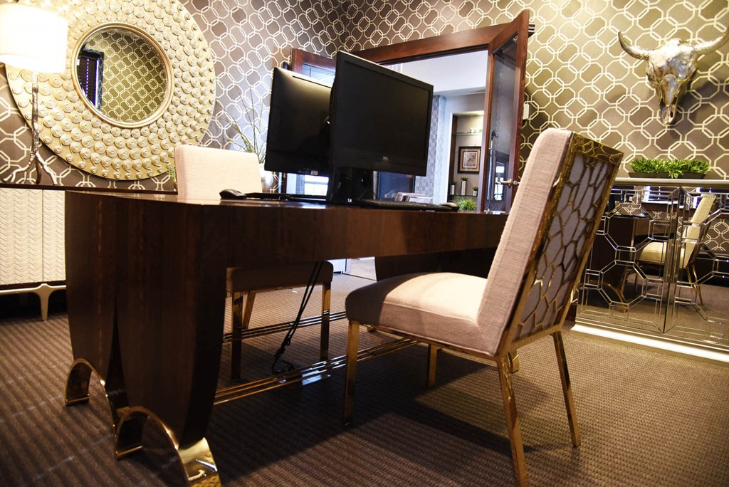 a desk with two monitors and a chair in a hotel room