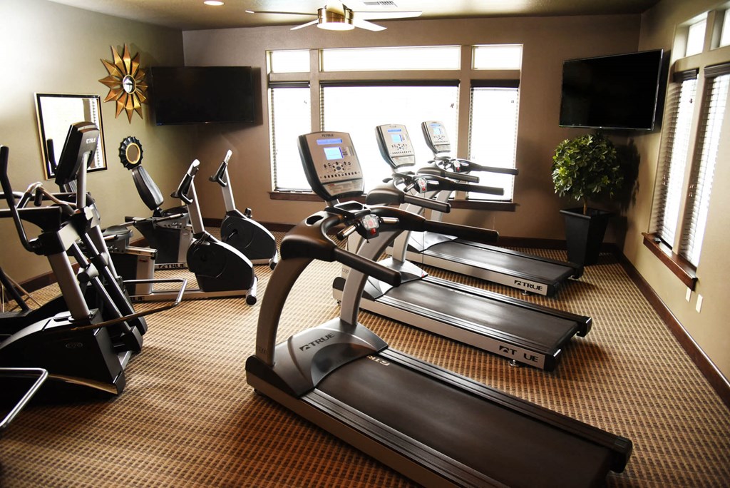 a gym with treadmills and televisions