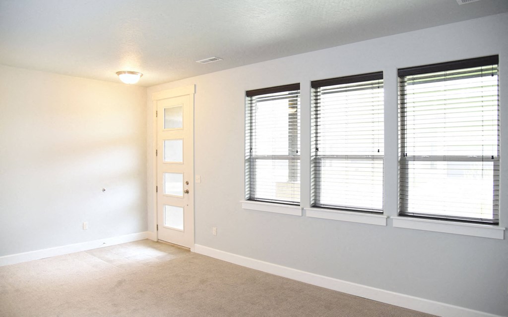 an empty living room with three windows and a door