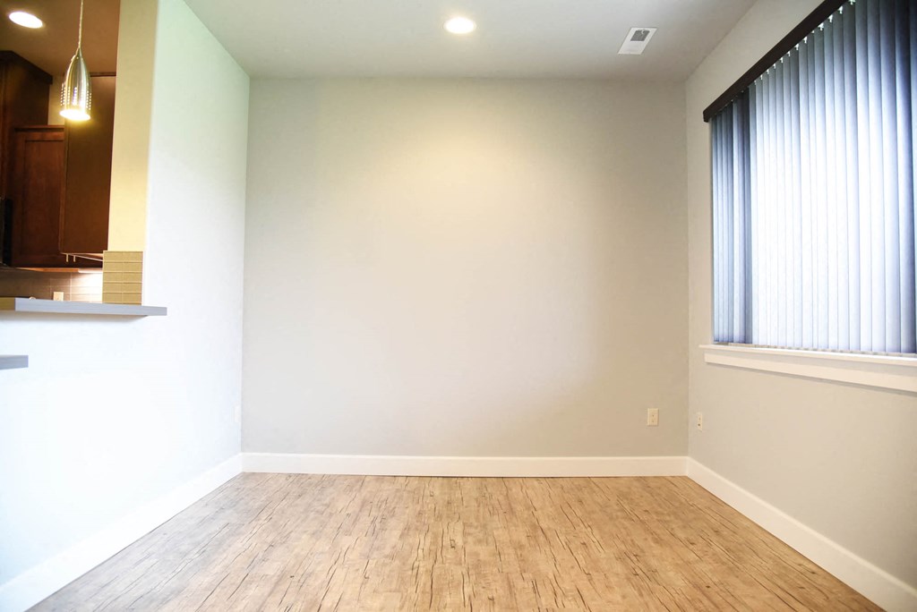 a empty living room with wood floors and a large window