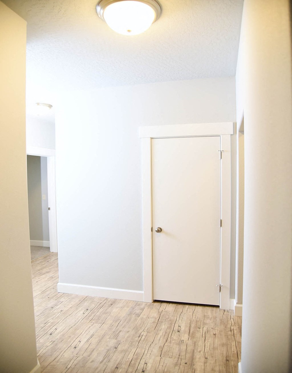 an empty hallway with white walls and a door to a closet