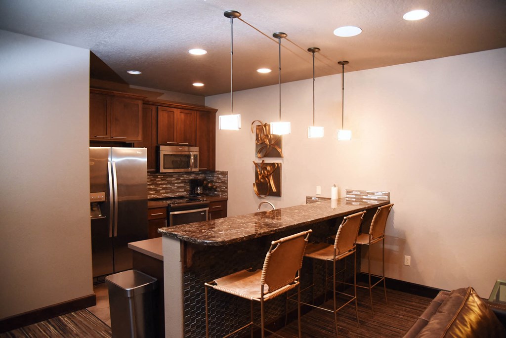 a kitchen with a bar and a stainless steel refrigerator