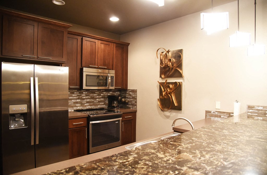a large kitchen with stainless steel appliances and granite counter tops