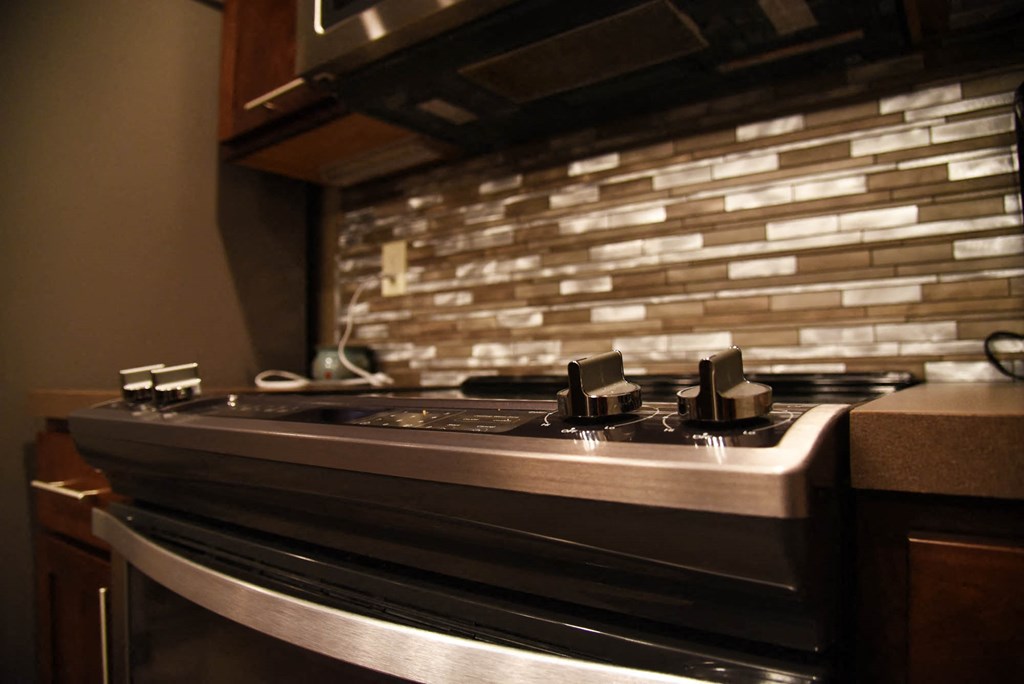 a kitchen with a stove top oven and a tile backsplash