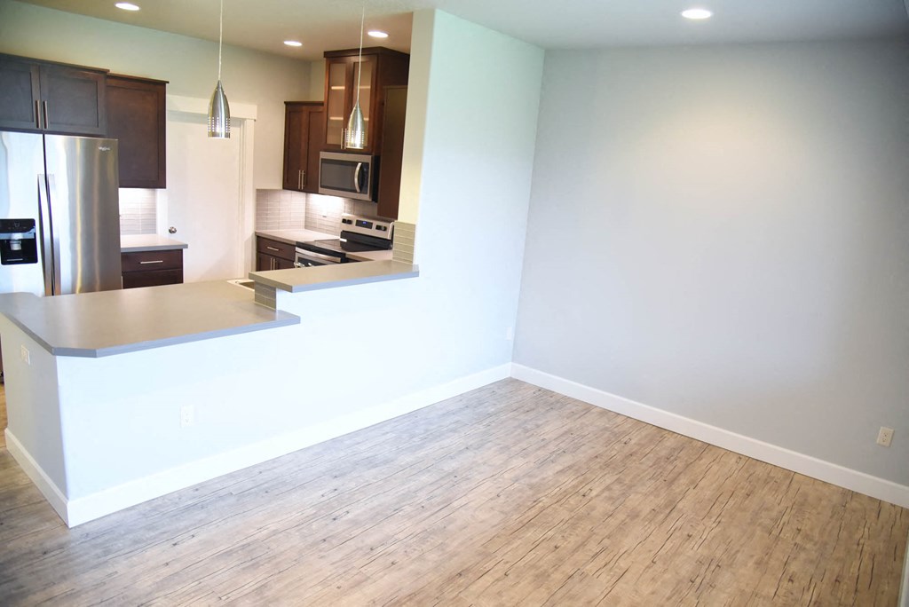an empty kitchen and living room with wood flooring