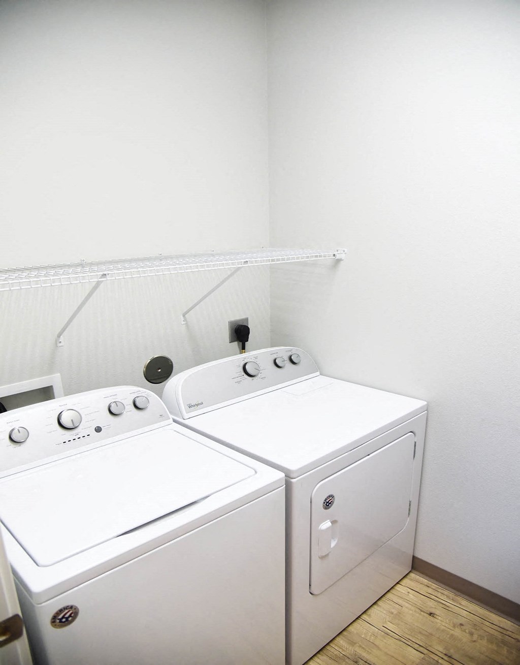 a washer and dryer in a room with white walls and wood floors