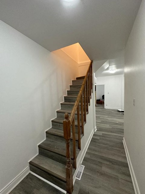a staircase in a home with white walls and wood floors