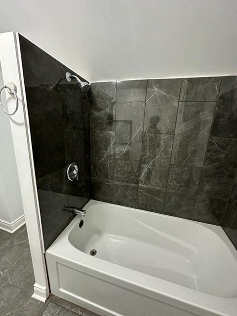 a bathroom with a white tub and a black wall