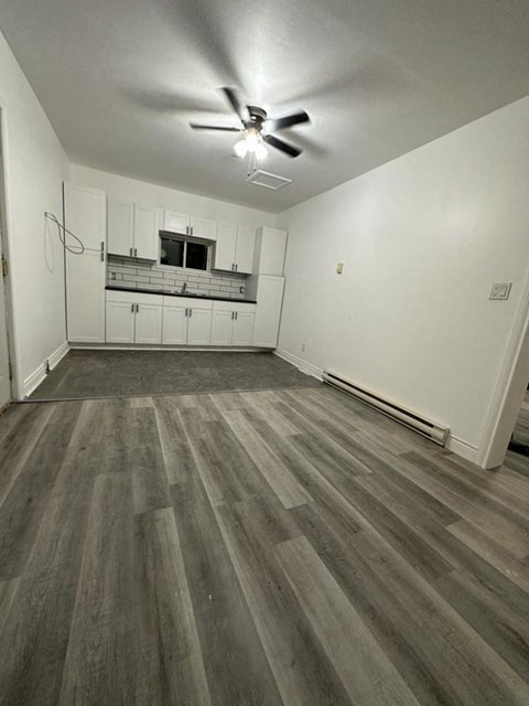 an empty living room and kitchen with wood flooring