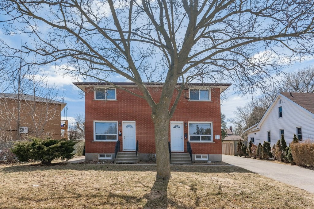 a red brick house with a large tree in front of it