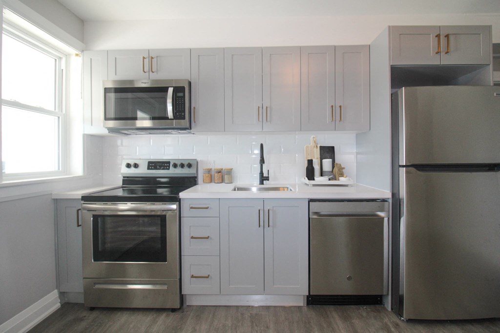 a white kitchen with stainless steel appliances and white cabinets