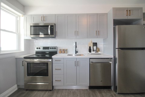 a white kitchen with stainless steel appliances and white cabinets