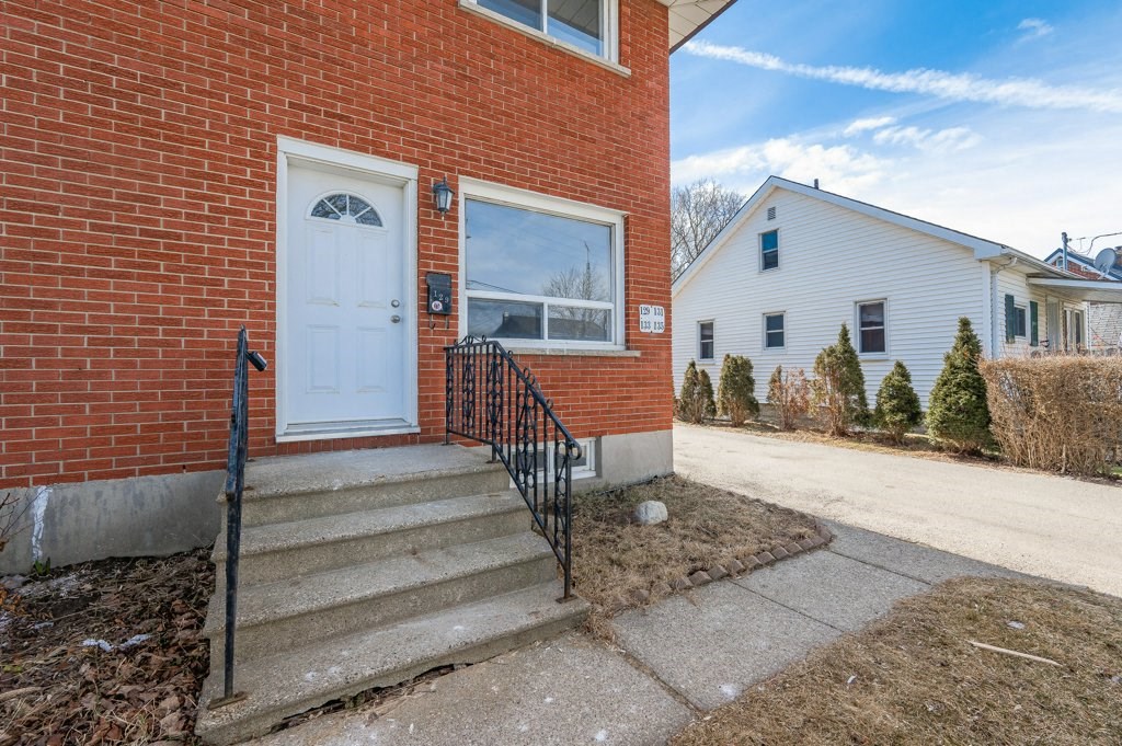 the front of a brick house with a white door and stairs
