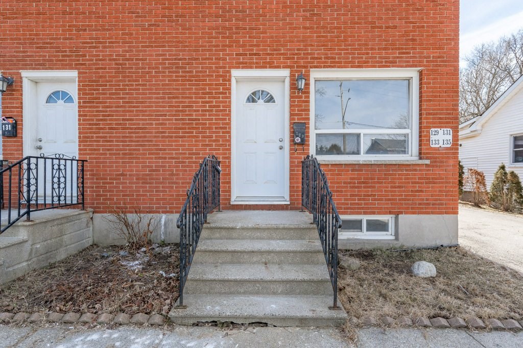 the front of a brick building with a white door and stairs