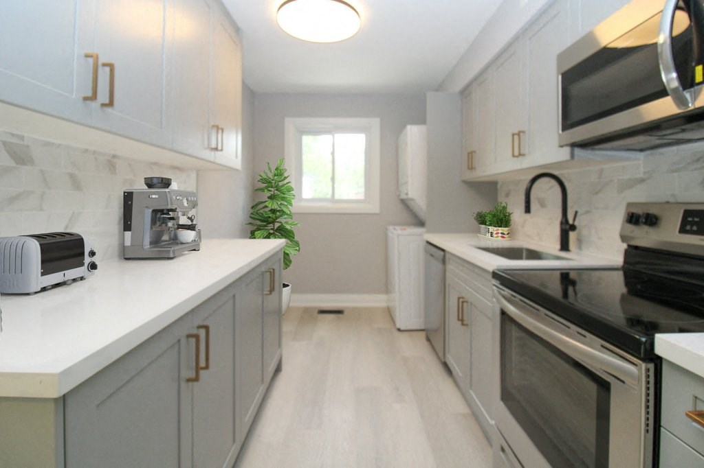 a kitchen with white cabinets and appliances and a window