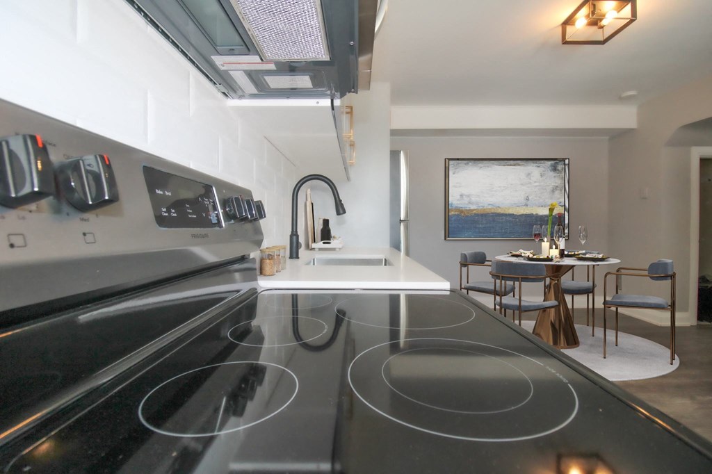 a kitchen with a stove and a sink and a dining table