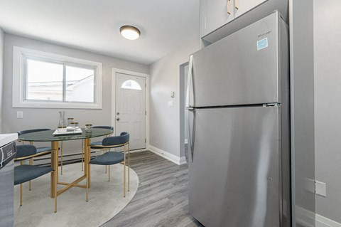 a kitchen and dining room with a stainless steel refrigerator and table