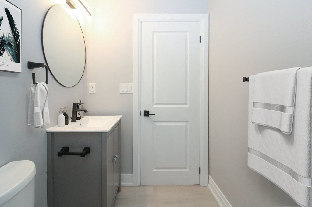 a small bathroom with a white door and a sink and a mirror